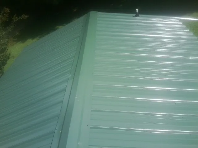 New green metal panels meeting at the ridge of a roof — Flat Roof Repair work by our crew in Bullard