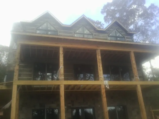 Dormers and porch framing on a large log home under construction — Roof Coating work by our crew in Bullard