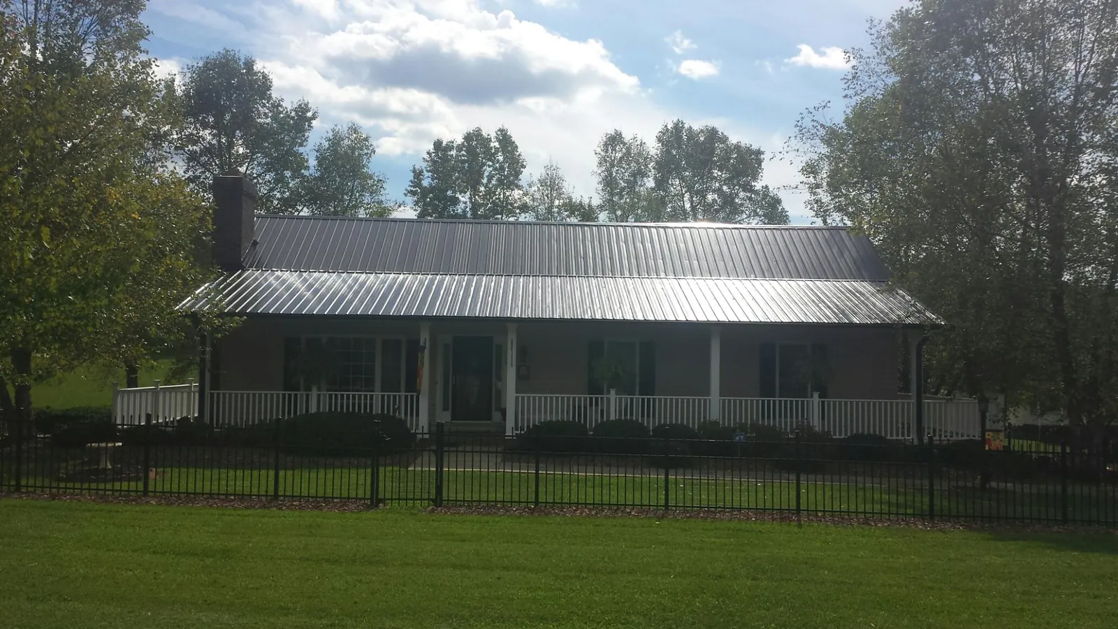 Gray metal roof on a brick ranch with a full width front porch — Gutter Guard Installation work by our crew in Bullard